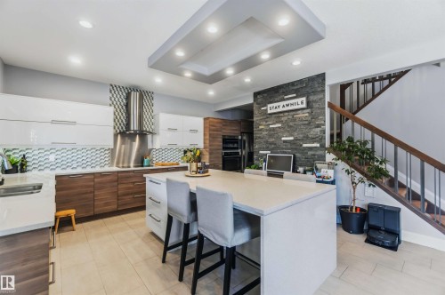 Kitchen with a large island, stainless steel appliances, patterned tile backsplash, recessed lighting, and a stone accent wall - 7 Etoile Cres, St. Albert, AB 