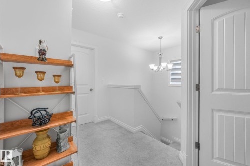 Plank-style interior doors, staircase with painted handrail, window with horizontal blinds, and a multi-light chandelier - 12843 67 Street Nw, Edmonton, AB 
