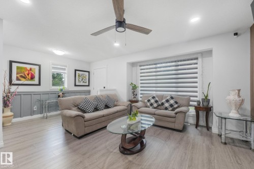 Wood-finish flooring, recessed lighting, ceiling fan, large window with blinds, and wainscoting - 12843 67 Street Nw, Edmonton, AB 