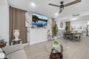 Wood-finish flooring throughout the open-concept living area, featuring a decorative slatted wall panel and a ceiling fan with integrated lighting - 12843 67 Street Nw, Edmonton, AB 