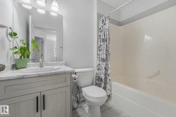 Bathroom featuring a vanity with a white countertop and undermount sink, a toilet, a shower-over-tub combination, and light wood-finish flooring - 