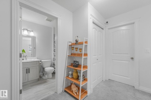 Bathroom featuring a single vanity with a white countertop and a mirror, accompanied by a toilet - 12843 67 Street Nw, Edmonton, AB 