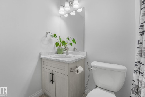 Single vanity with a white countertop and integrated sink, chrome faucet, and a wall-mounted mirror - 12843 67 Street Nw, Edmonton, AB 