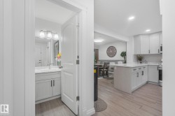 Modern kitchen featuring white cabinetry, a center island with countertop seating, and light wood-finish flooring - 
