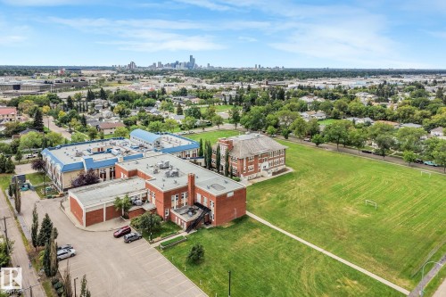 Expansive grounds featuring a manicured lawn, paved parking areas, and mature trees - 12843 67 Street Nw, Edmonton, AB 