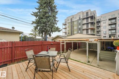 Expansive wooden deck with a red privacy fence and a covered carport structure - 12843 67 Street Nw, Edmonton, AB 