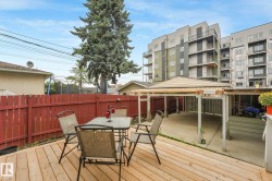 Expansive wooden deck with a red privacy fence and a covered carport structure - 