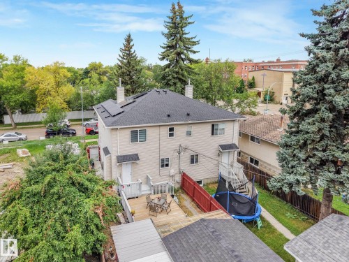 Two-story residence featuring light-toned siding, a dark shingle roof with solar panels, and prominent white chimneys - 12843 67 Street Nw, Edmonton, AB 