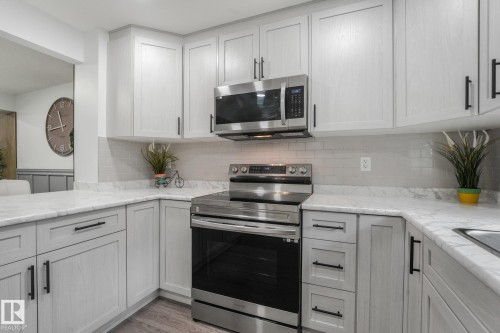 Grey shaker cabinetry with matte black hardware, stainless steel appliances, marble-finish countertops, and subway tile backsplash - 12843 67 Street Nw, Edmonton, AB 