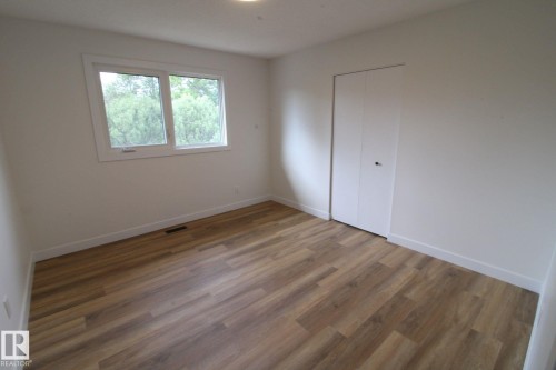 Wood-finish flooring, white walls, white trim, a double-pane window, and a bi-fold closet door - 4224 110 Street Nw, Edmonton, AB 