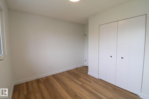 Wood-finish flooring, white walls, and a built-in closet with white bifold doors - 4224 110 Street Nw, Edmonton, AB 