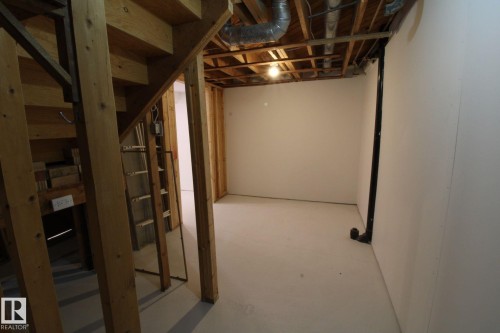 Unfinished basement space with exposed wood framing, white painted walls, and light-colored concrete flooring - 4224 110 Street Nw, Edmonton, AB 