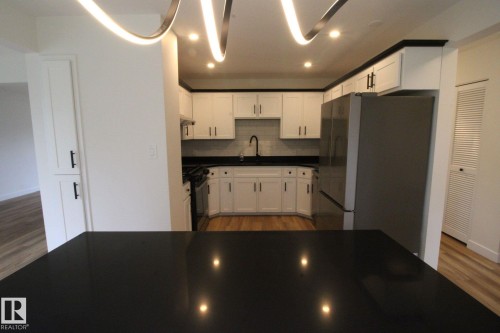 Modern kitchen featuring white cabinetry, dark countertops, recessed lighting, and wood-finish flooring - 4224 110 Street Nw, Edmonton, AB 