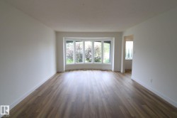 Spacious interior with neutral white walls, wood-finish flooring, and a curved bay window - 
