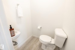 Compact powder room featuring a wall-mounted sink, a two-piece toilet, and wood-finish flooring - 