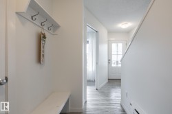 Entryway with wood-finish flooring, a built-in bench, and a wall-mounted coat rack - 