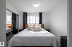 Recessed window with dark drapery panels, wood-finish headboard, and mirrored closet doors - 