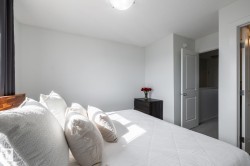 Recessed ceiling lighting, light gray wall paint, and a wood-finish bed frame - 