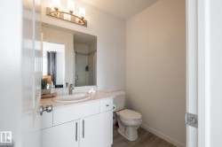 White vanity with an integrated sink, brushed nickel faucet, large mirror, and three-light vanity fixture - 