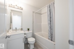 Bathroom with a vanity featuring an integrated sink, a toilet, and a combined tub and shower with tile surround - 