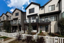 Townhome exterior featuring horizontal siding, vertical siding, and a white picket fence - 