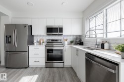Kitchen featuring stainless steel appliances, white cabinetry, wood-finish flooring, a subway tile backsplash, and recessed lighting - 