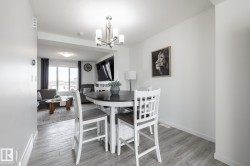 Open-concept living space featuring wood-finish flooring, a contemporary chandelier, and a large window - 