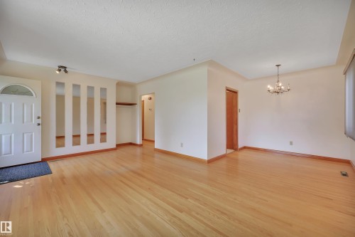 Hardwood flooring throughout, a front entry door with an arched window, a built-in decorative wall feature with mirrored panels, and a chandelier lighting fixture - 13416 102 Street Nw, Edmonton, AB 
