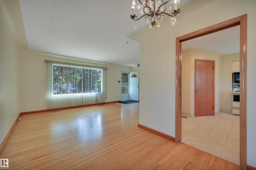 Hardwood-finish flooring, large picture window, decorative chandelier, wood-trimmed doorway, and white tiled flooring - 13416 102 Street Nw, Edmonton, AB 