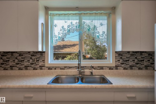 Dual basin stainless steel sink with a high-arc faucet, set within a light-toned countertop - 13416 102 Street Nw, Edmonton, AB 