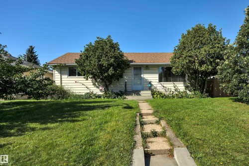 Single-story dwelling with light-colored siding, a brown shingle roof, and a front entry door with a storm door - 13416 102 Street Nw, Edmonton, AB 