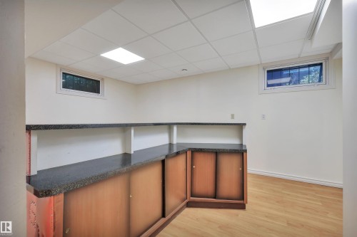 Built-in cabinetry with dark countertops and wood-finish sliding doors - 13416 102 Street Nw, Edmonton, AB 
