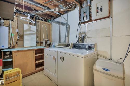 Utility area featuring a water heater, electrical panels, and exposed ceiling joists - 13416 102 Street Nw, Edmonton, AB 