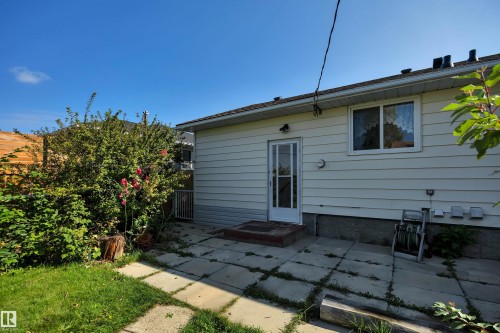 Backyard featuring a concrete patio, a grass lawn, and mature shrubs - 13416 102 Street Nw, Edmonton, AB 