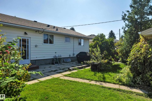 Expansive backyard with a manicured lawn, concrete patio, and mature landscaping - 13416 102 Street Nw, Edmonton, AB 