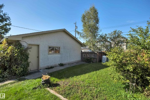 Detached garage with stucco exterior, rear entry door, and a single window - 13416 102 Street Nw, Edmonton, AB 