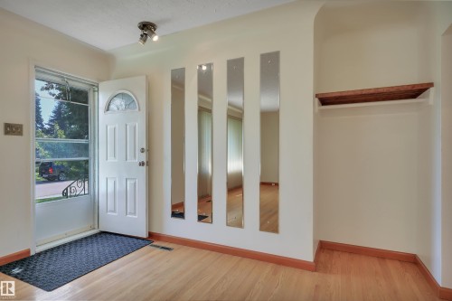 Entryway featuring wood-finish flooring, a white paneled door with an arched window, and a built-in shelf - 13416 102 Street Nw, Edmonton, AB 