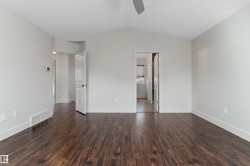 Vaulted ceiling with a ceiling fan, dark wood-finish flooring, and white trim - 