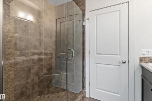 Glass-enclosed shower with a tiled surround, integrated shower bench, and mosaic tile accents - 17535 110 Street Nw, Edmonton, AB 