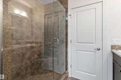 Glass-enclosed shower with a tiled surround, integrated shower bench, and mosaic tile accents - 