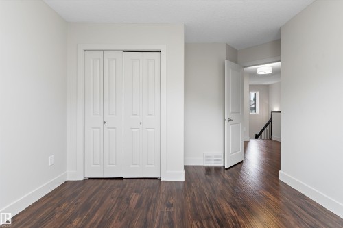 Wood-finish flooring, bi-fold closet doors, white interior door, recessed lighting, and a contemporary ceiling fixture - 17535 110 Street Nw, Edmonton, AB 