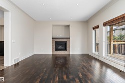 Dark-tone wood flooring, recessed lighting, crown molding, integrated fireplace with stone tile surround, and outdoor deck access - 