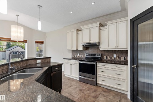 Kitchen featuring a dual basin sink, stainless steel appliances, white cabinetry, a tiled backsplash, and recessed lighting - 17535 110 Street Nw, Edmonton, AB 