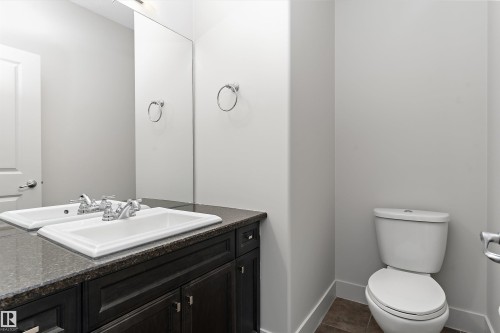 Single vanity with an integrated rectangular sink, dark wood-finish cabinetry, and a dark stone-finish countertop - 17535 110 Street Nw, Edmonton, AB 