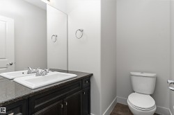 Single vanity with an integrated rectangular sink, dark wood-finish cabinetry, and a dark stone-finish countertop - 