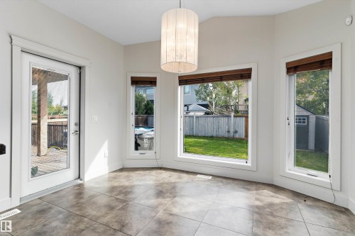 Tiled flooring, multiple windows, built-in window treatments, glass-paneled exterior door, and a suspended light fixture - 17535 110 Street Nw, Edmonton, AB 