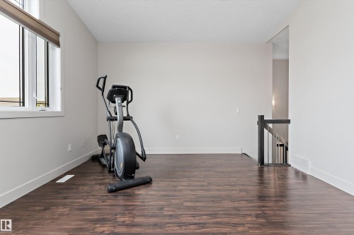 Wood-finish flooring, white trim, light neutral wall color, and a dark wood newel post and balusters - 17535 110 Street Nw, Edmonton, AB 