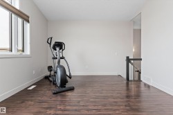 Wood-finish flooring, white trim, light neutral wall color, and a dark wood newel post and balusters - 