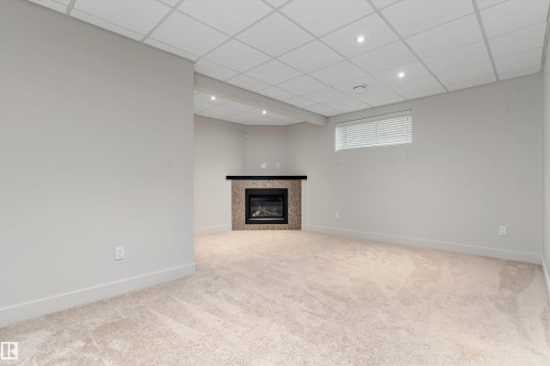 Corner fireplace with a dark mantel, recessed lighting, and carpeted flooring - 17535 110 Street Nw, Edmonton, AB 
