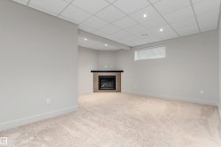 Corner fireplace with a dark mantel, recessed lighting, and carpeted flooring - 